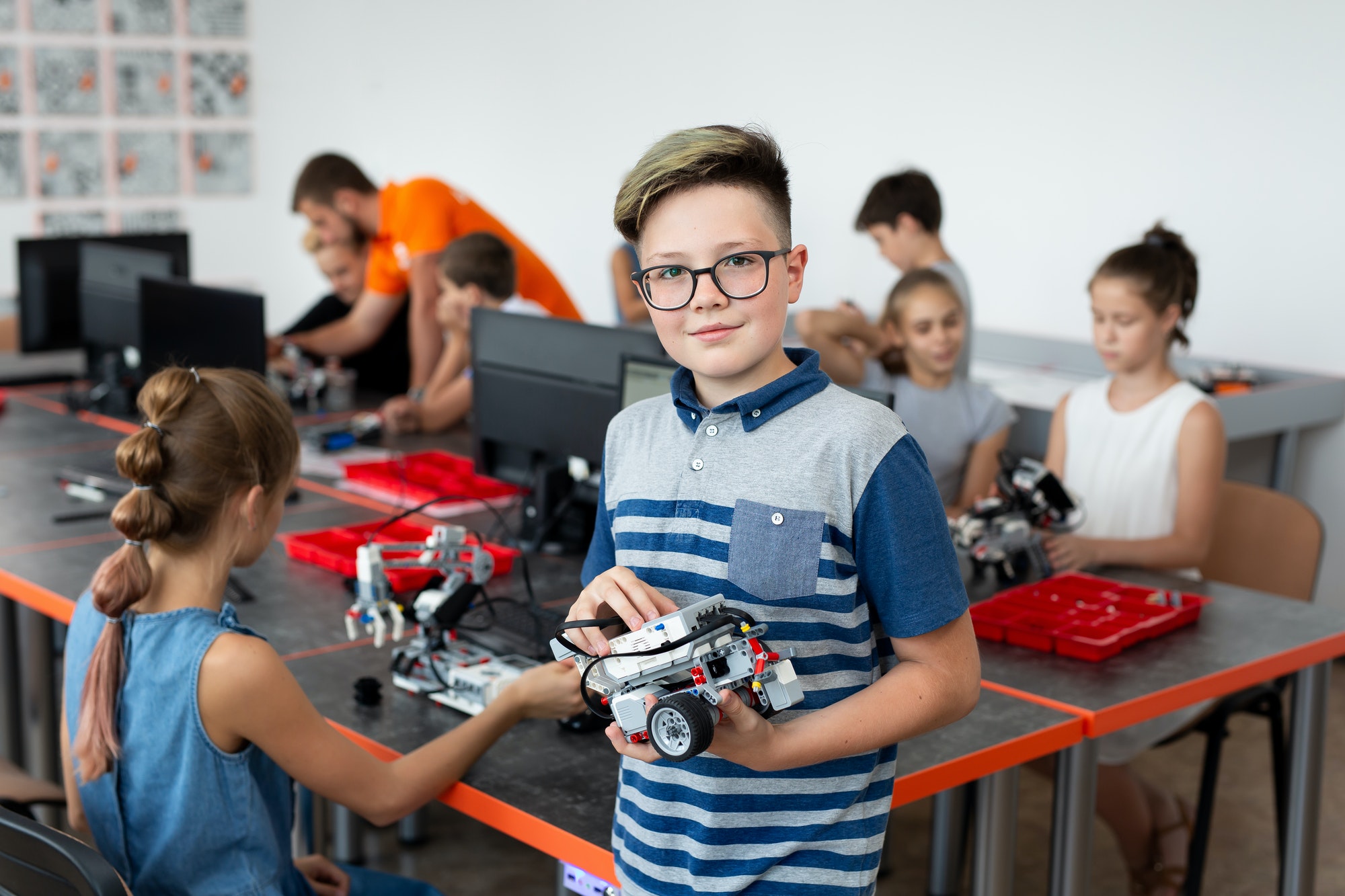 Portrait Of Male Student Building Robot Vehicle In After School Computer Coding Class.